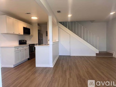 A spacious kitchen with white cabinets and a wooden floor.