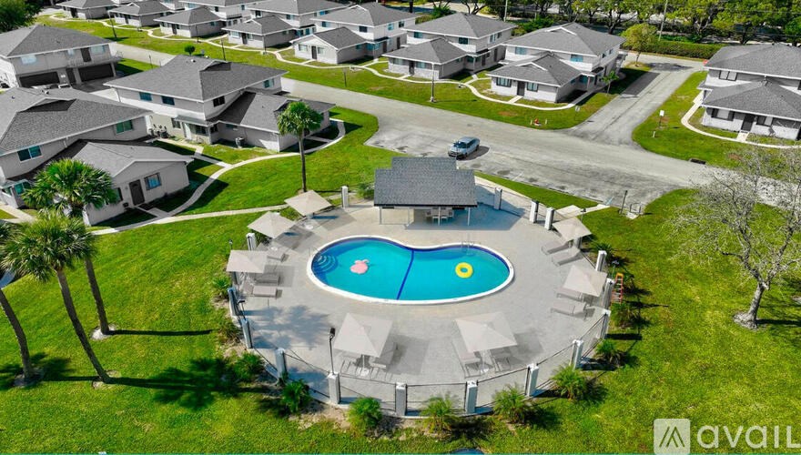 A bird's eye view of a neighborhood with a swimming pool in the foreground.