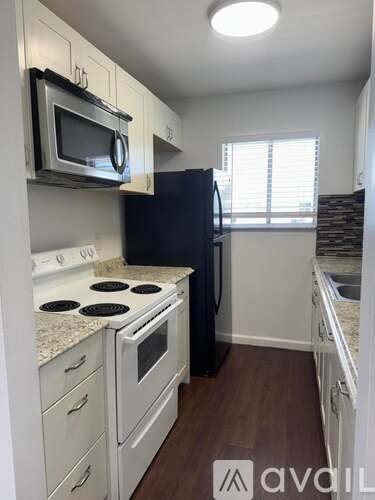 A kitchen with white cabinets and a black refrigerator.