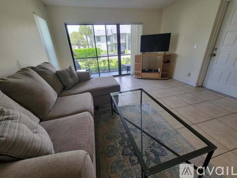 A living room with a grey couch and a glass coffee table.