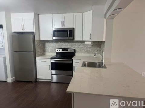 A kitchen with white cabinets and a stainless steel refrigerator.