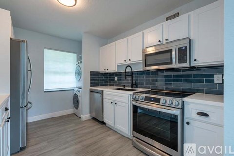 A kitchen with white cabinets and a stainless steel refrigerator.