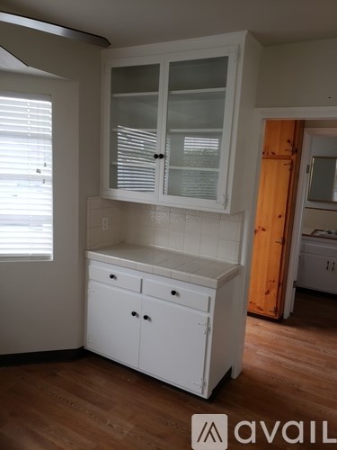 A white kitchen cabinet with a glass door is in the foreground.