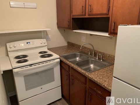 A kitchen with a white stove, sink and refrigerator.