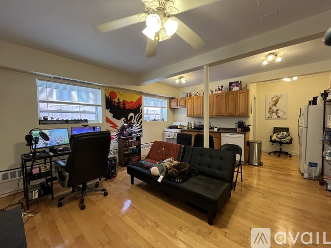 A living room with a black couch and a fan.