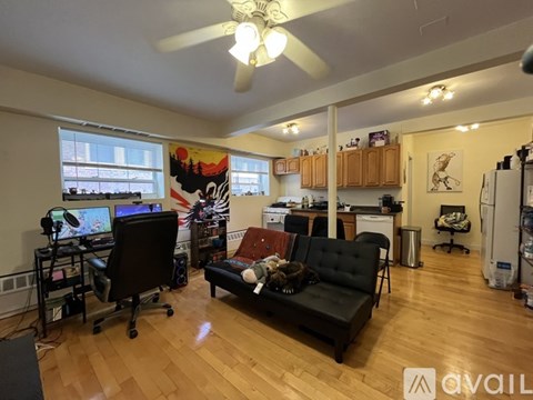 A living room with a black couch and a fan.