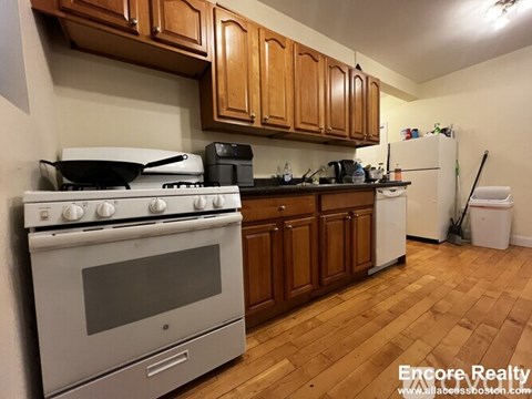 A kitchen with a stove, oven, and wooden cabinets.