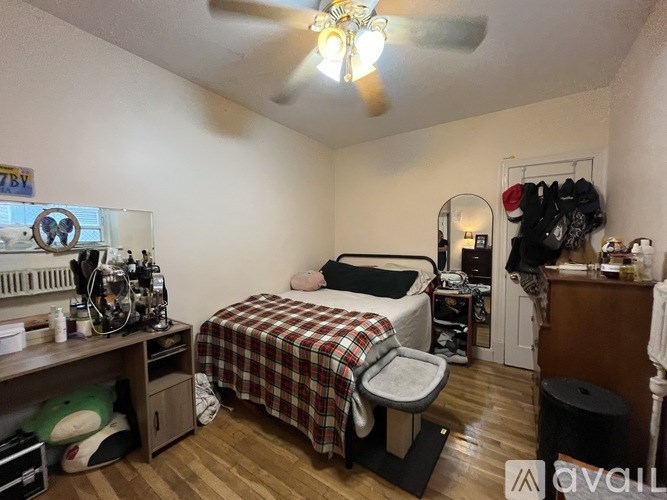 A bedroom with a bed, a desk, a chair, and a ceiling fan.