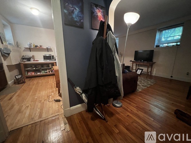 A room with a wooden floor and a coat hanging on a hook.