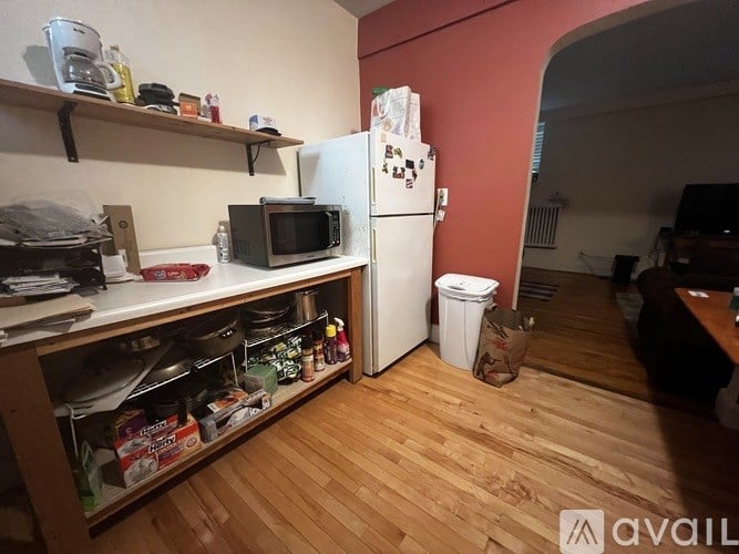A kitchen with a white fridge, wooden floor, and a microwave on the counter.