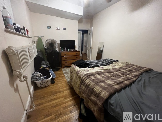 A bedroom with a bed, dresser, and a radiator.