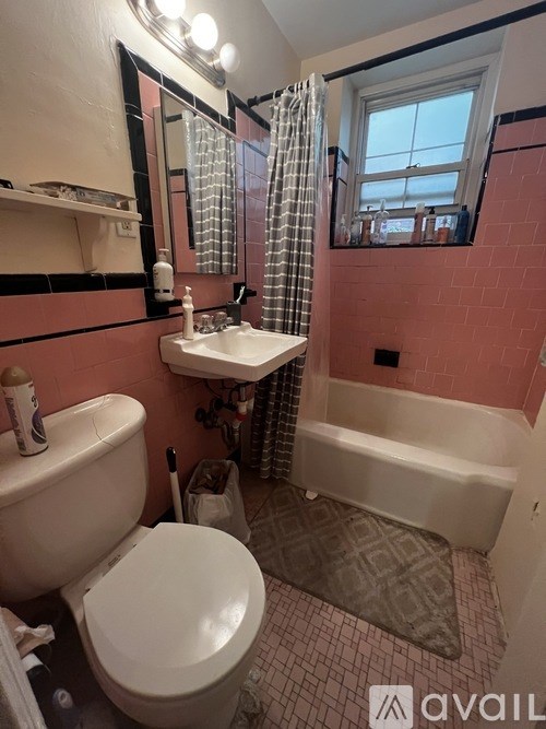 A bathroom with pink walls and a white toilet.
