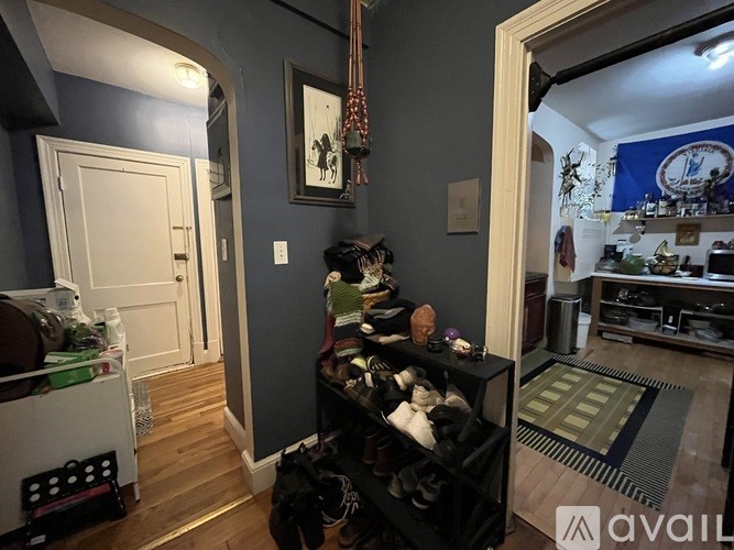 A room with a black shelf filled with shoes and a painting hanging on the wall.
