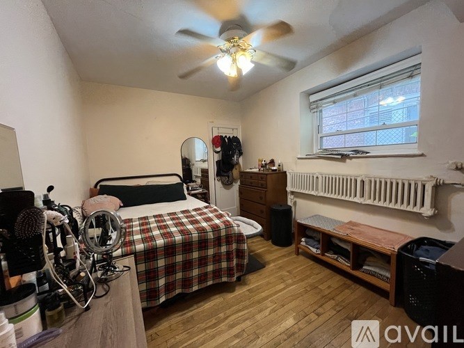 A bedroom with a bed, dresser, and a window with a white frame.