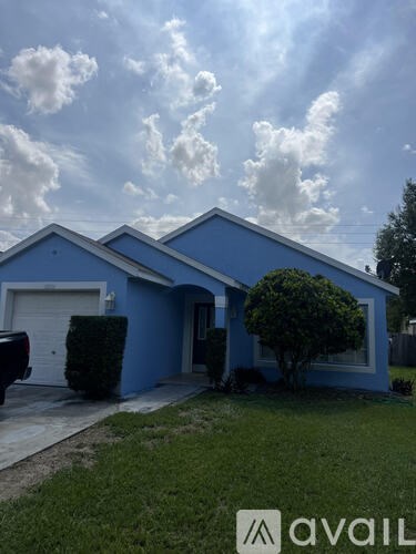 A blue house with a white garage door and a tree in front.