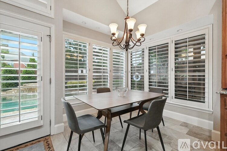 A dining room with a table, chairs, and a chandelier.