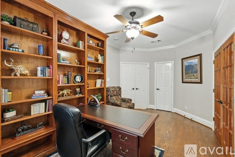 A room with a ceiling fan and a desk with a chair.