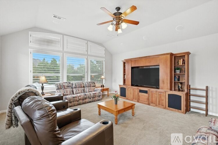 A living room with a brown leather couch and a wooden entertainment center.
