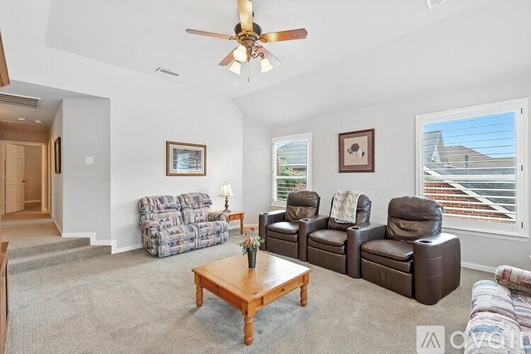 A living room with a grey sofa, a brown leather chair, a wooden coffee table and a ceiling fan.