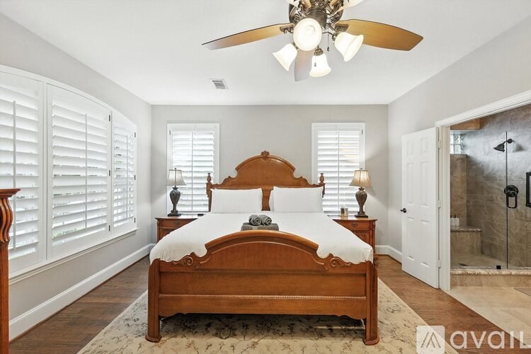 A bedroom with a large bed and a ceiling fan.