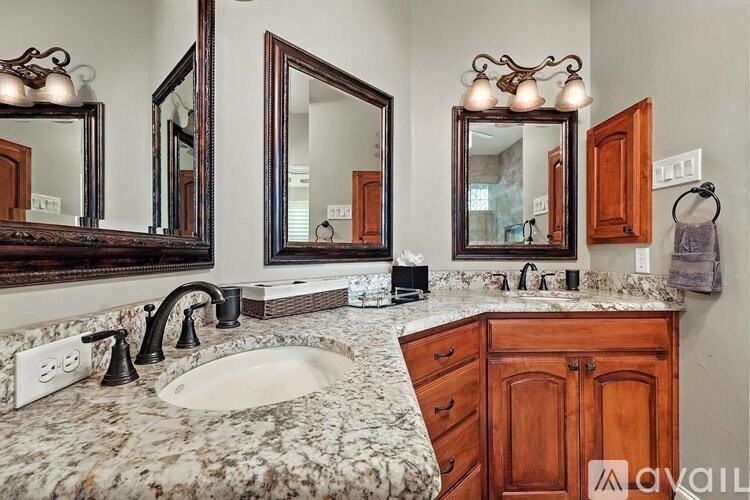 A bathroom with a marble countertop and wooden cabinets.