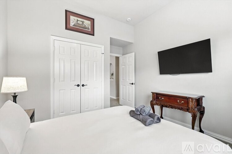 A bedroom with a bed, a desk, and a television.