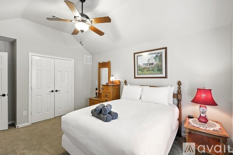 A bedroom with a bed, dresser, mirror, and a ceiling fan.