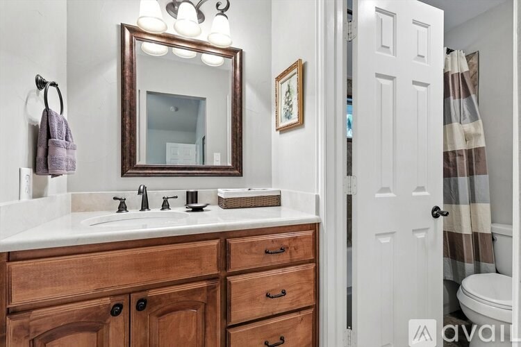 A bathroom with a wooden vanity and a mirror above it.