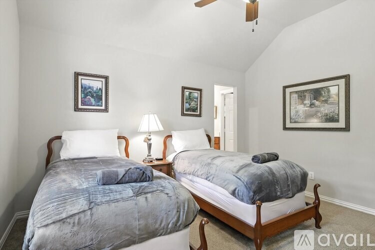 Two twin beds in a room with white walls and a ceiling fan.