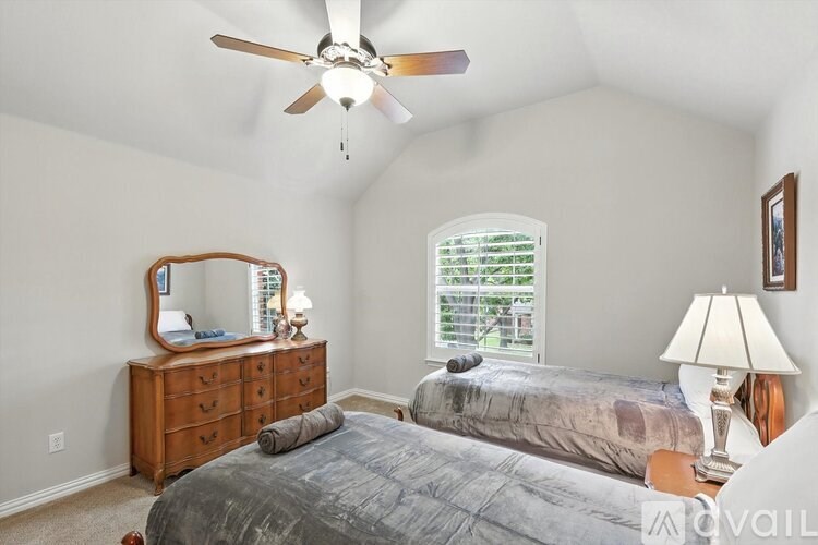 A bedroom with a bed, dresser, and window.