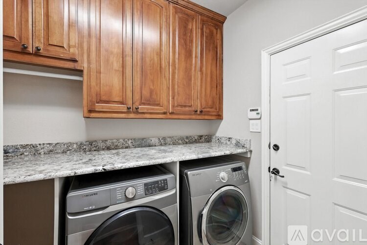 A washer and dryer in a laundry room with wooden cabinets.