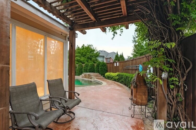 A patio with chairs and a table is covered by a roof.