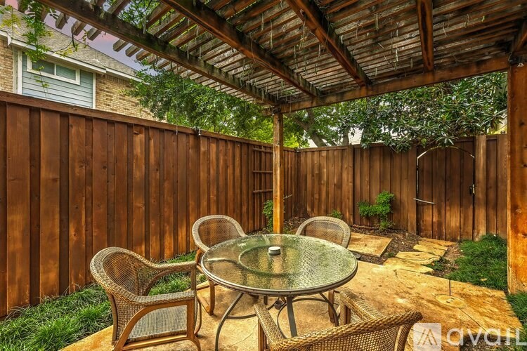 A patio with a glass table surrounded by a wooden fence.