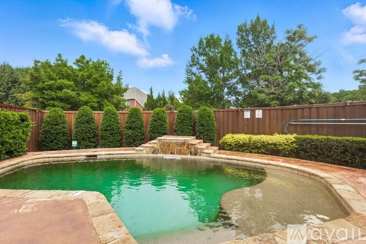 A pool surrounded by a wooden fence and greenery.