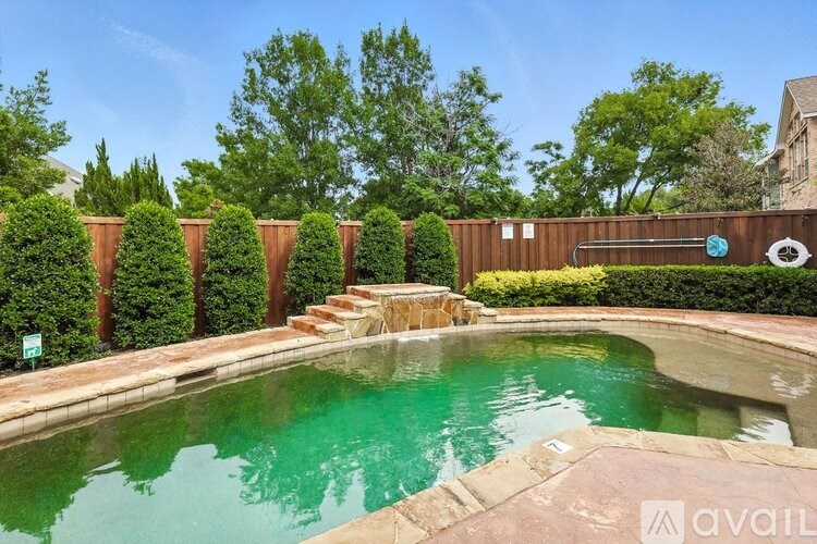 A pool surrounded by a wooden fence and green trees.