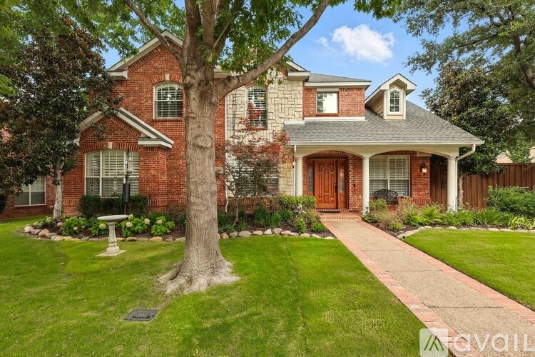A red brick house with a tree in front.