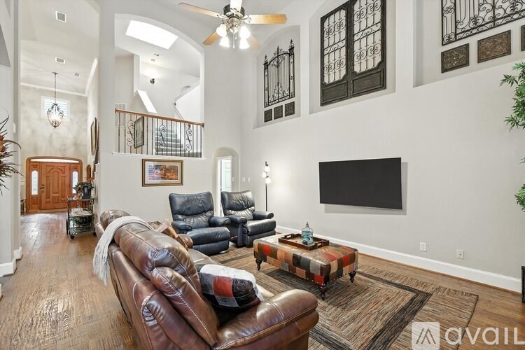 A living room with a brown leather couch and a flat screen TV mounted on the wall.