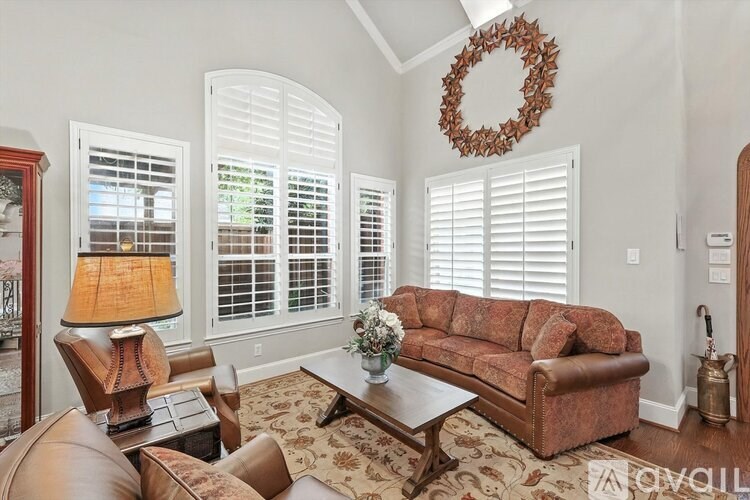 A living room with a brown couch, a coffee table, and a wreath on the wall.