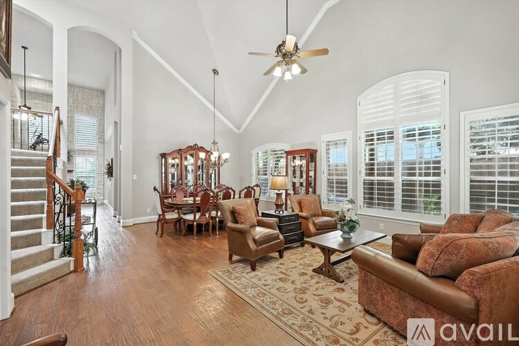 A spacious living room with a staircase on the left and a dining area in the background.