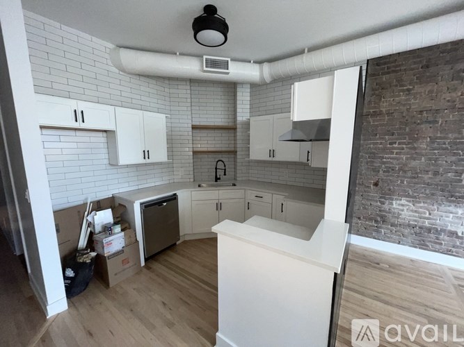 A kitchen with white cabinets and a brick wall.