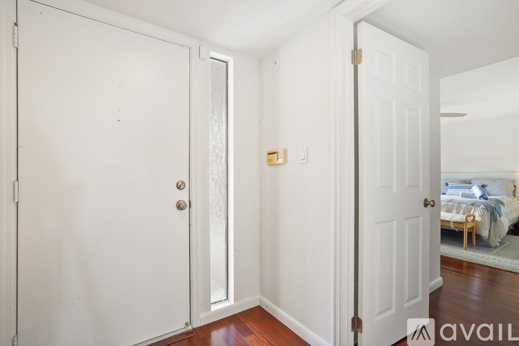 A white door with a gold handle is open to a bedroom.