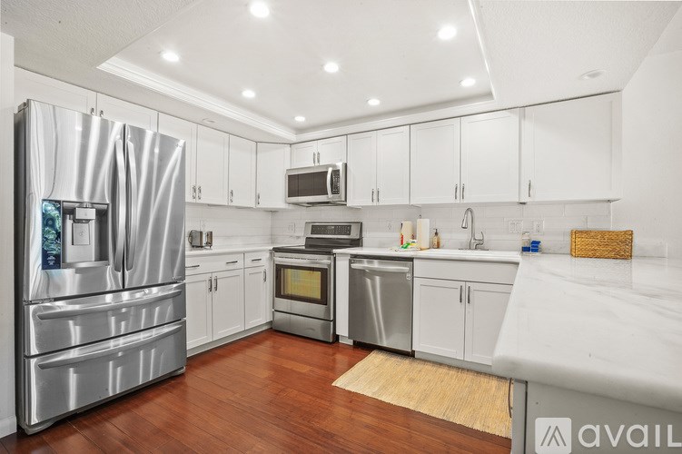 A kitchen with white cabinets and a wooden floor.