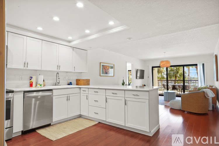 A kitchen with white cabinets and a wooden floor.