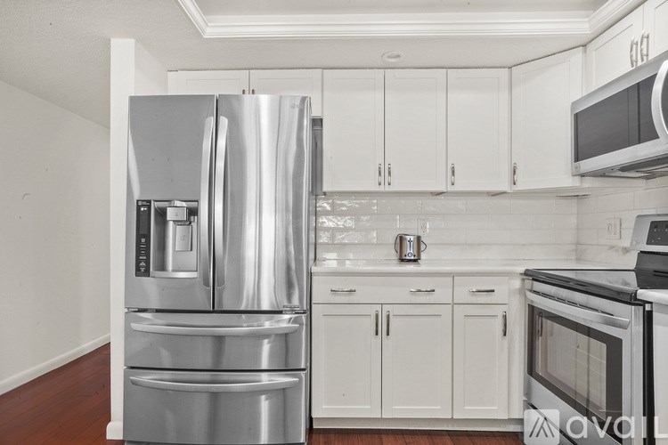 A kitchen with a stainless steel refrigerator and white cabinets.