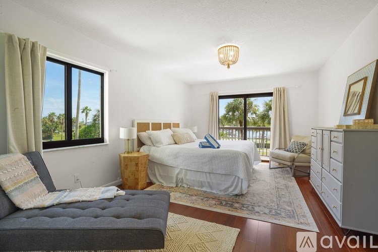 A bedroom with a large bed and a balcony overlooking the trees.