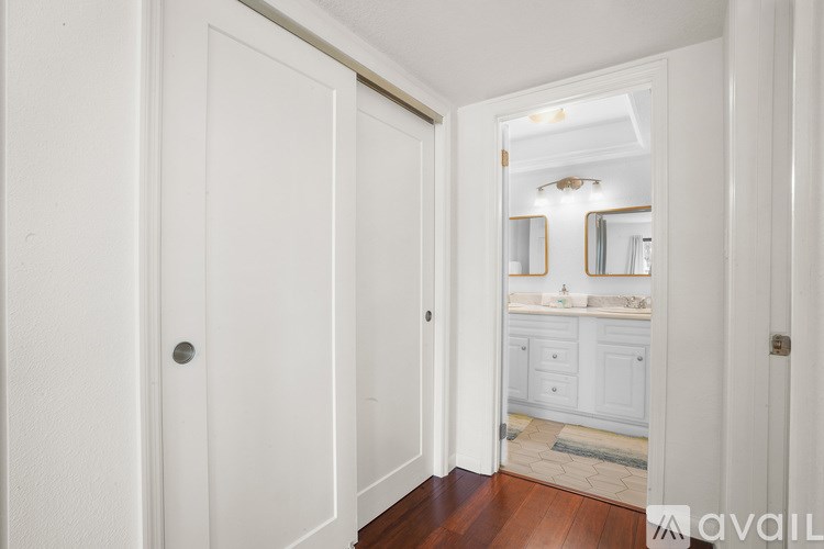 A white door opens to a bathroom with a mirror and a sink.
