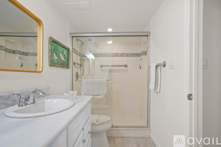 A bathroom with a white toilet, sink, and shower.