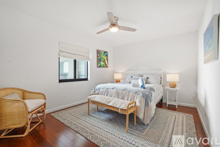 A bedroom with a bed, chair, and rug.