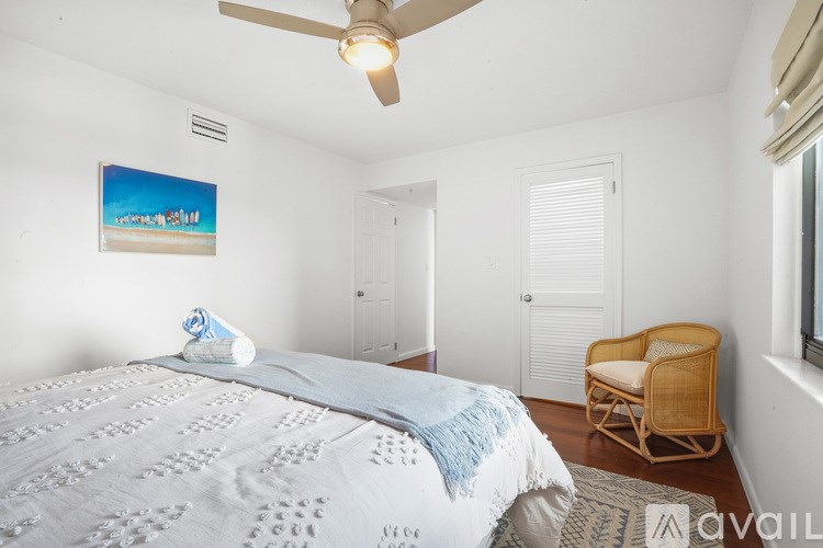 A bedroom with a bed, chair, and painting on the wall.