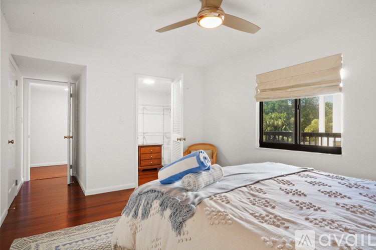 A bedroom with a bed, a ceiling fan, and a window with blinds.